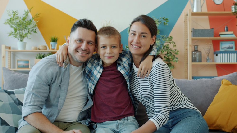 Two adults and a child sitting close together on a sofa