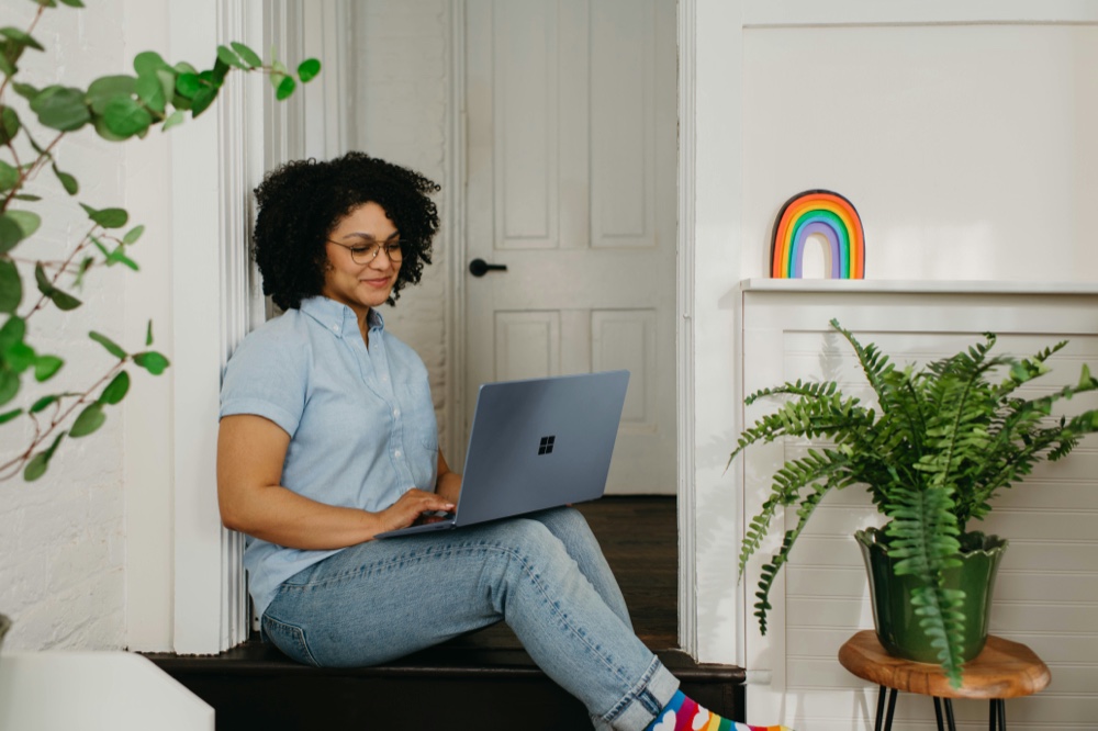 A person sitting on the floor at home, working on a laptop